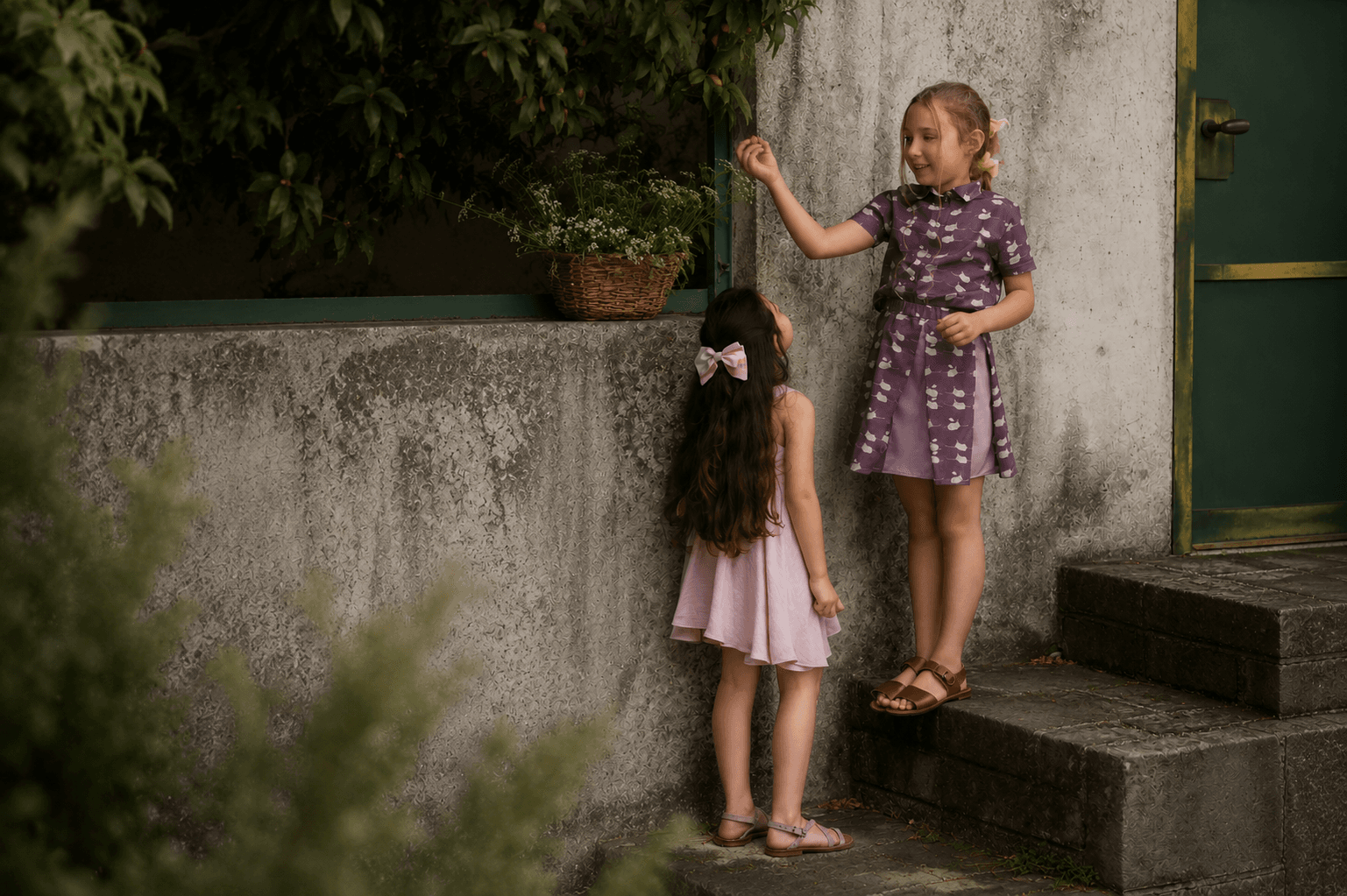 Due bambine Farway Milano con abiti estivi accanto a un muretto in pietra